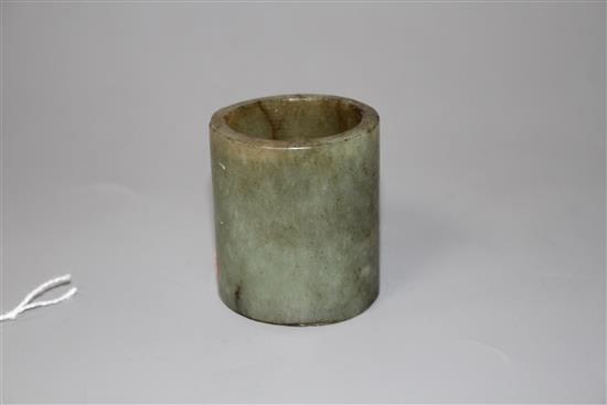 A Chinese celadon and brown jade cylinder, probably archaic, H. 4.6cm